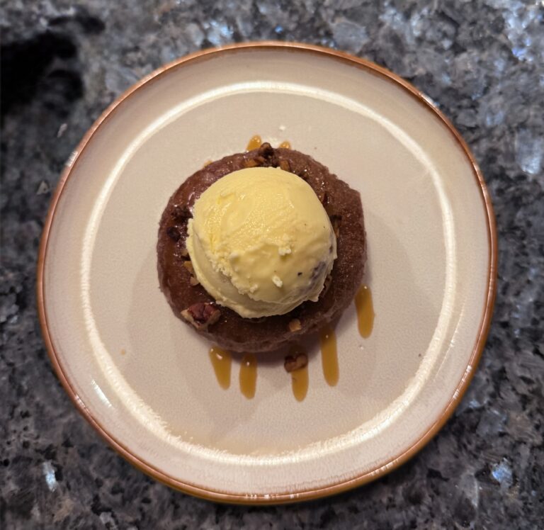 Apple Cider Donuts on a white plate with caramel and pecans
