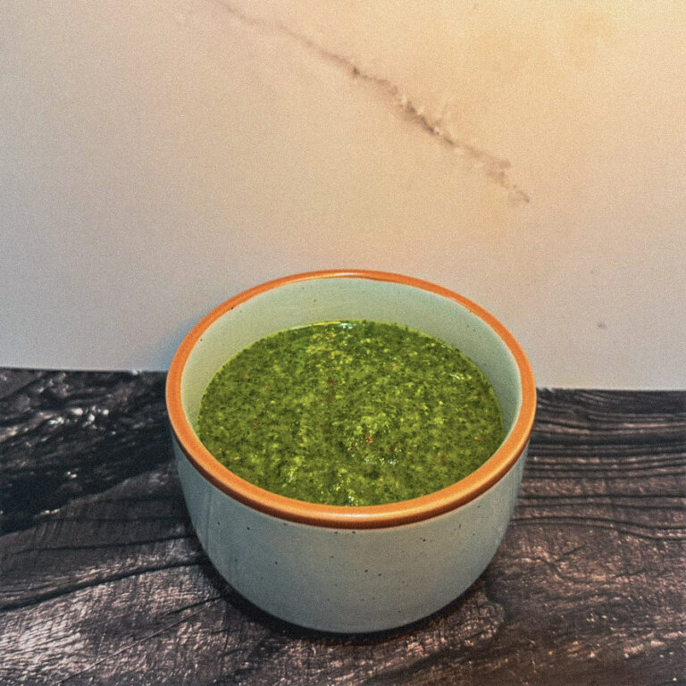 Chimichurri sauce in a ceramic bowl on dark wood
