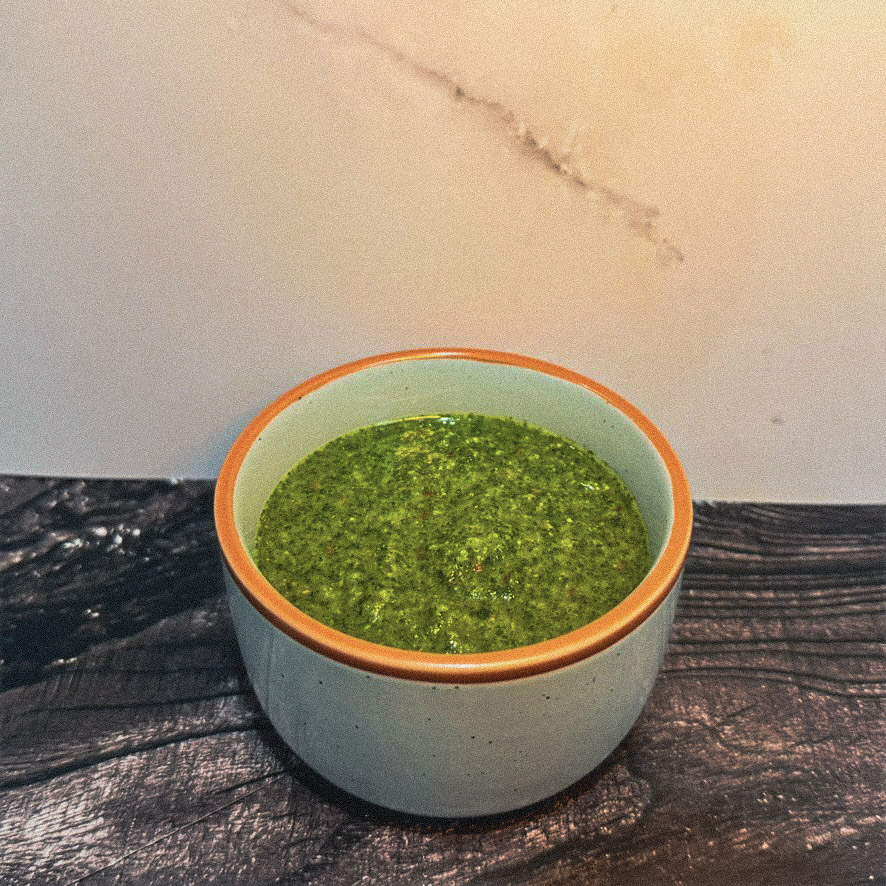 Chimichurri sauce in a ceramic bowl on dark wood