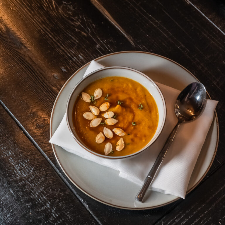Sweet Potato Bisque in a warm shallow bowl with toasted pepitas and crème fraîche